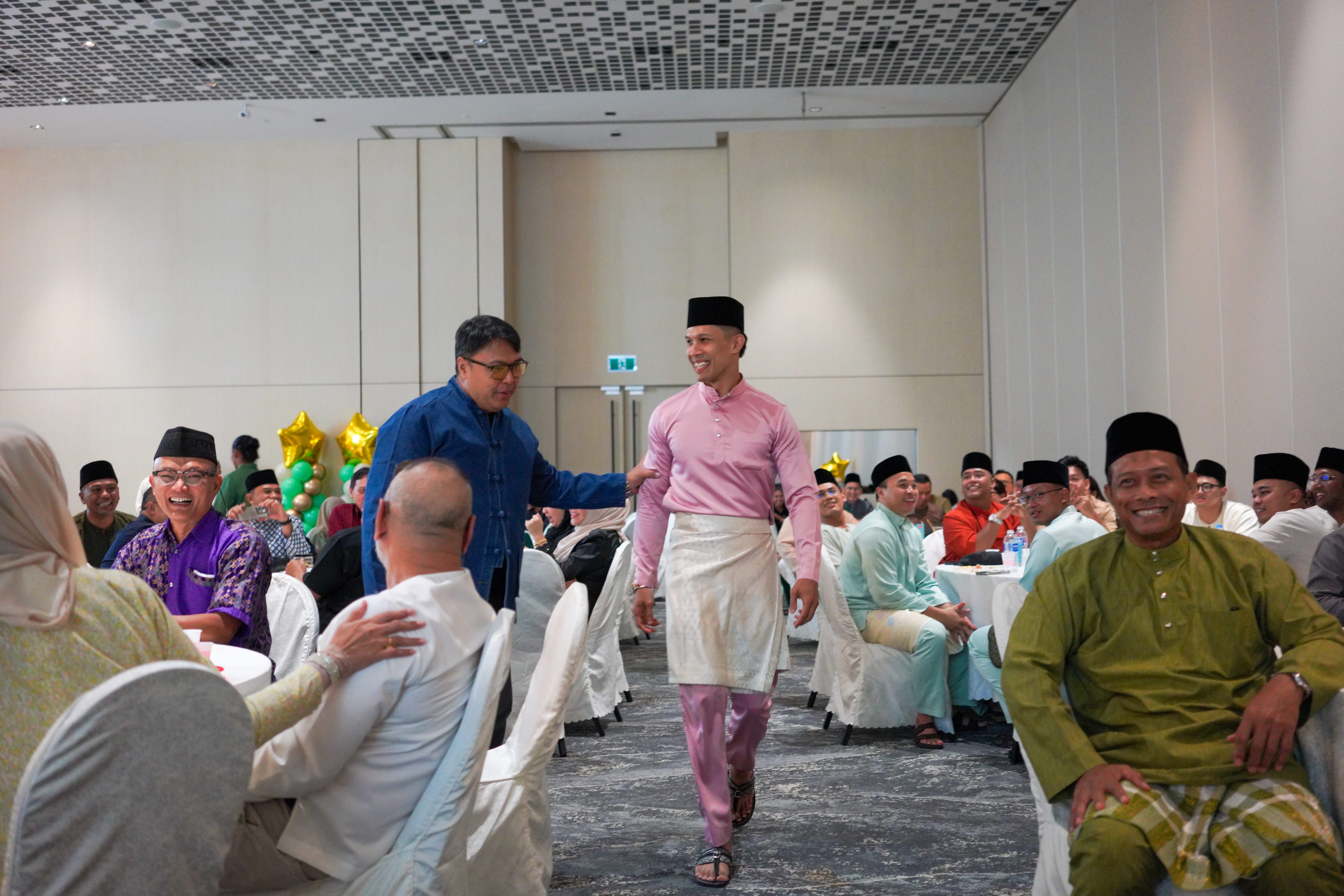 Participants walking between banquet tables during an interactive stage segment as guests watch and laugh.